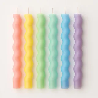 Seis velas de corpo ondulado formando um degradê de coral, amarelo, verde, azul e lilás
